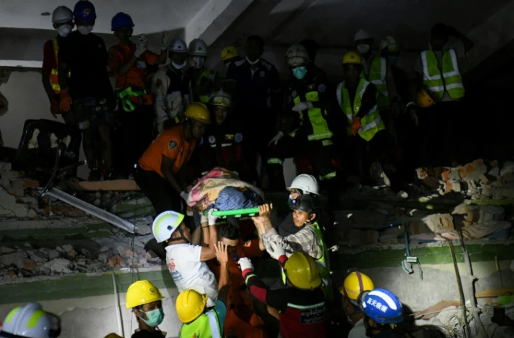Des secouristes transportent une victime piégée sous les décombres de l'immeuble Sky Villa Condominium détruit à Mandalay, en Birmanie, le 30 mars 2025
