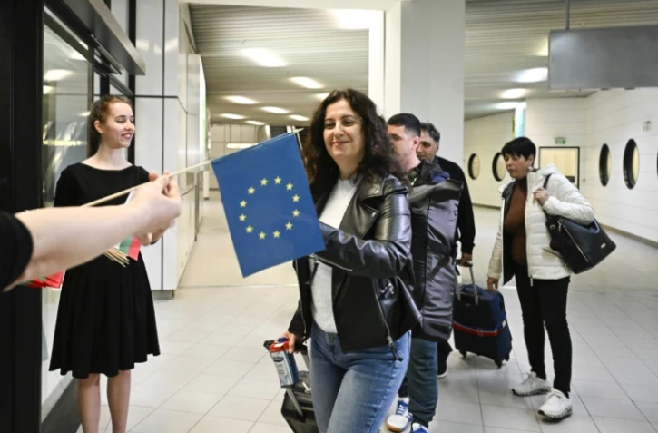 Des passagers arrivant de Berlin recoivent des drapeaux européen et bulgare après l'entrée partielle de la Bulgarie dans l'espace Schengen, à l'aéoport de Sofia le 31 mars 2024