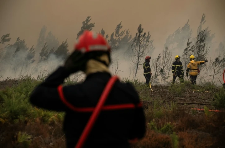Des pompiers arrosent la lisière d'une forêt lors d'un incendie de forêt près de la ville de Lège-Cap-Ferret, en Gironde, le 25 juillet 2026