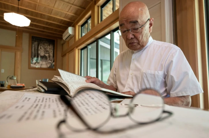 Le prêtre bouddhiste Eiichi Shinohara regarde le journal d'une femme qui s'est fait escroquer des millions de yens, lors d'une interview avec l'AFP dans son temple à Narita, à l'est de Tokyo, le 5 septembre 2023