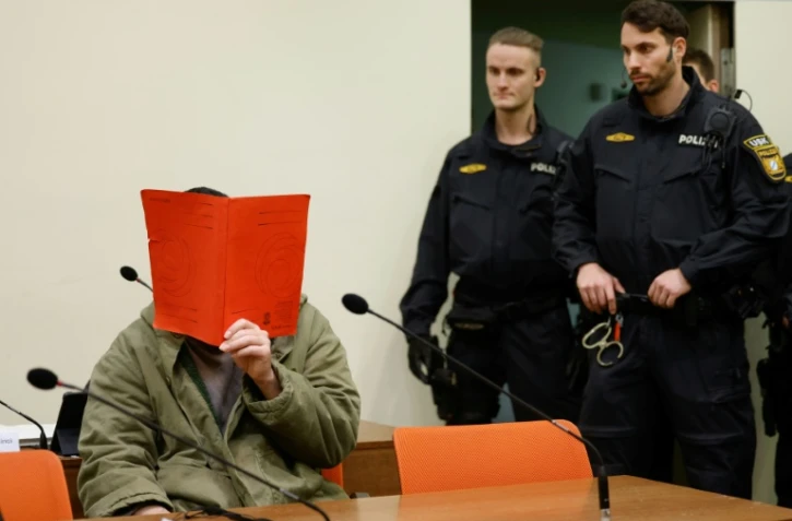 L'Afghan Farhad N. (g.), le visage caché derrière un dossier, est assis dans la salle d'audience du tribunal, le 16 janvier 2026 à Munich, pour le début de son procès pour avoir foncé en voiture dans la foule à Munich en 2025