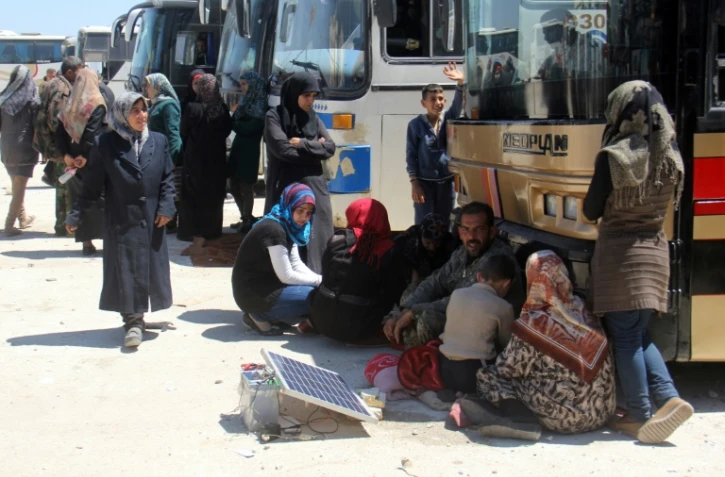 Des Syriens originaires de Foua et Kafraya rechargent leurs téléphones à Rachidine le 20 avril 2017 en attendant leur évacuation