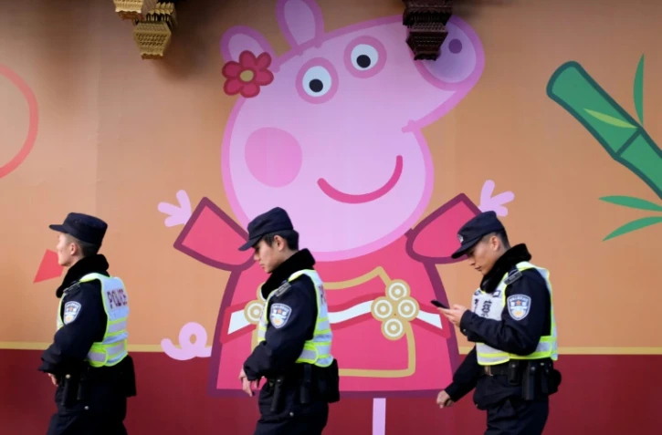 Des policiers passent devant l'effigie de Peppa Pig sur un mur, le 25 janvier 2019 à Shanghai