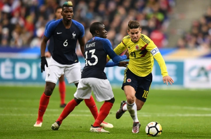 Le milieu français Paul Pogba (g) regarde son homologue N'Golo Kanté (c) à la lutte avec le milieu colombien James Rodriguez lors d'un amical au Stade de France, à Saint-Denis, le 23 mars 2018