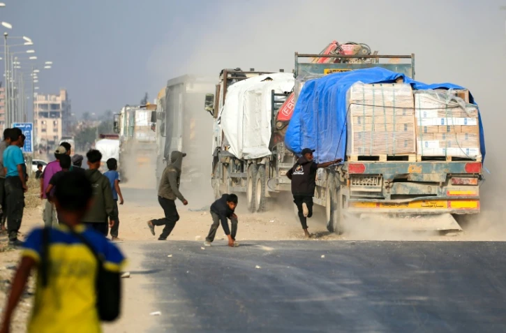 Un Palestinien tente de monter à bord d'un camion circulant sur la route Salah al-Din, dans le centre de la bande de Gaza, près de Deir al-Balah, alors que des personnes tentent d'obtenir de l'aide humanitaire, le 9 novembre 2025