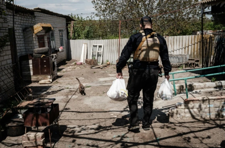 Un policier ukrainien apporte de la nourriture à des habitants de Novomykolaïvka, dans l'est de l'Ukraine, le 11 mai 2022
