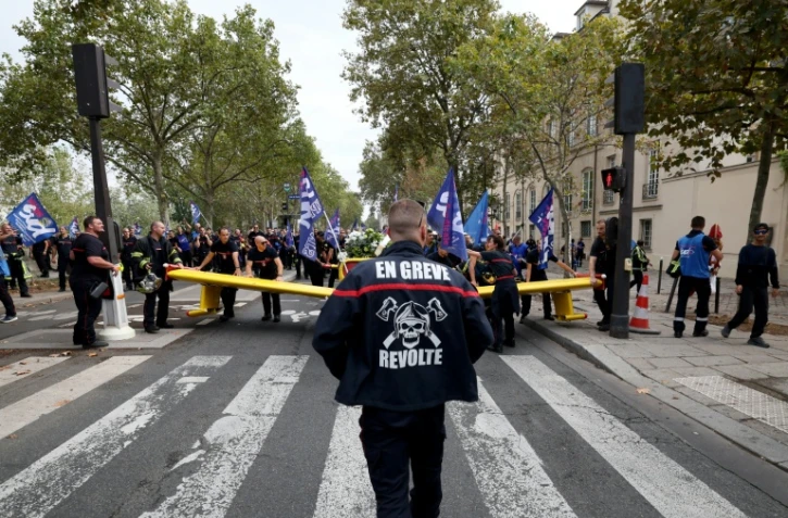 Un pompier portant une inscription "En grève" participe à une manifestation organisée par une large coalition de syndicats, à Paris, le 28 septembre 2026