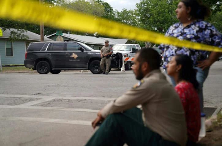 Des habitants, sonnés, assis sur le trottoir non loin de l'école primaire endeuillée, à Uvalde, au Texas, le 24 mai 2022