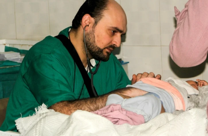 Photographie transmise le 29 avril 2016 par l'Association ds médecins indépendants (IDA), montrant le docteur Mohammad Wassim Maaz oscultant un enfant dans un hôpital syrien d'Alep le 20 février 2016.