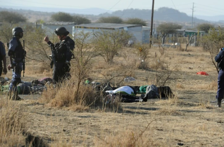 Des policiers devant des corps de manifestants sur lesquels ils ont ouvert le feu près de la mine de Marikana (Afrique dus Sud) le 16 août 2012