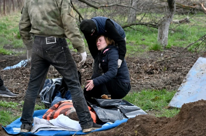 Une femme en larmes lors des fouilles pour exhumer le corps de son mari tué à Andriivka, près de Kiev, le 11 avril 2022