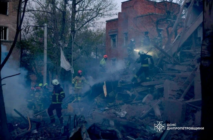 Photo prise et diffusée par le Service d'État des situations d'urgence de l'Ukraine, le 25 avril 2026, montrant des secouristes dans les décombres d'un immeuble résidentiel après une attaque russe à Dnipro, dans le centre-est du pays 