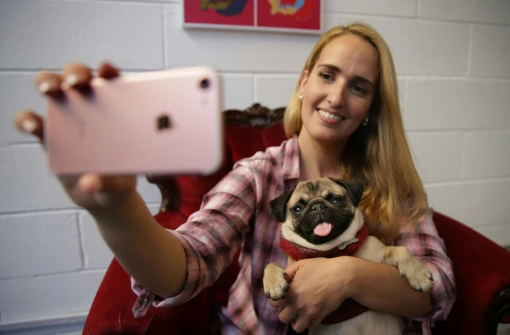 Aida Martinez prend un selfie avec Mia, star du Pugs & Pals cafe, bar dédié aux amoureux du carlin ("pug", en anglais), à Brick Lane, dans l'est de Londres, le 27 octobre 2017
