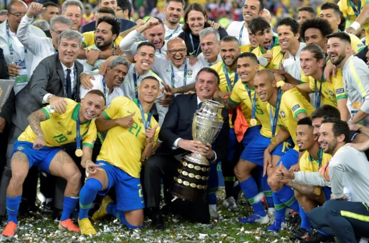 Le président du Brésil Jair Bolsonaro (c) pose avec les joueurs et le trophée après la victoire face au Pérou en finale de la Copa América, le 7 juillet 2019 à Rio de Janeiro