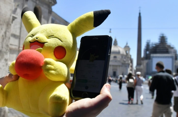 Un joueur tient une mascotte de Pokémon et joue au Pokémon Go sur son portable, le 19 juillet 2016 à Rome.