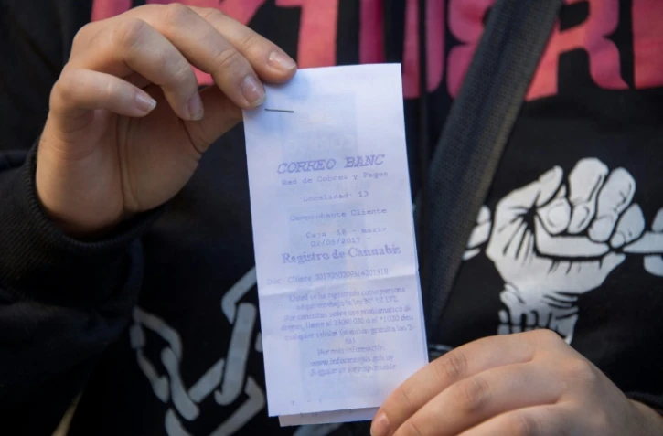 Une femme montre son ticket prouvant son inscription au registre d'acheteurs de marijuana mis en place par l'Etat, à Montevideo, le 2 mai 2017