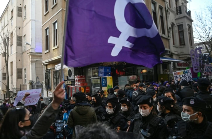 Un drapeau féministe brandi devant les forces de l'ordre lors d'une marche organisée à l'occasion de la journée mondiale des droits des femmes, à Istanbul, le 8 mars 2021