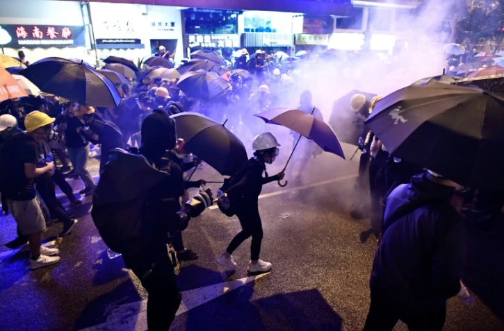 Des manifestants tentent de se protéger des nuages de gaz lacrymogène, le 28 juillet 2019 à Hong Kong