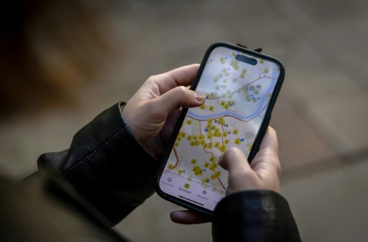 Ruta Gaskauskaite présente sur son téléphone une application qui permet aux utilisateurs de trouver les abris les plus proches, à Vilnius, le 28 mai 2026, en Lituanie