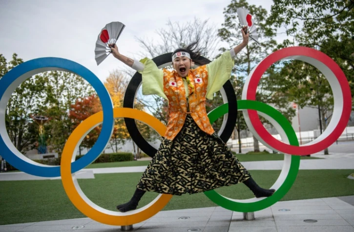 La fan des Jeux olympiques Kyoko Ishikawa pose devant les anneaux installés devant le nouveau stade olympique national à Tokyo, le 19 décembre 2020.