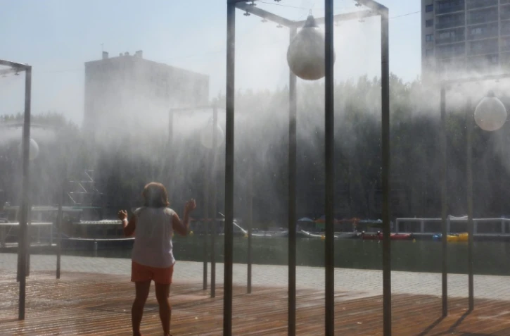 Une femme se rafraîchit sous un brumisateur le 24 juillet 2019 à Paris