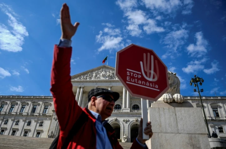 Un homme tient une pancarte "Stop à l'euthanasie" lors d'une manifestation devant le Parlement à Lisbonne, le 20 février 2020
