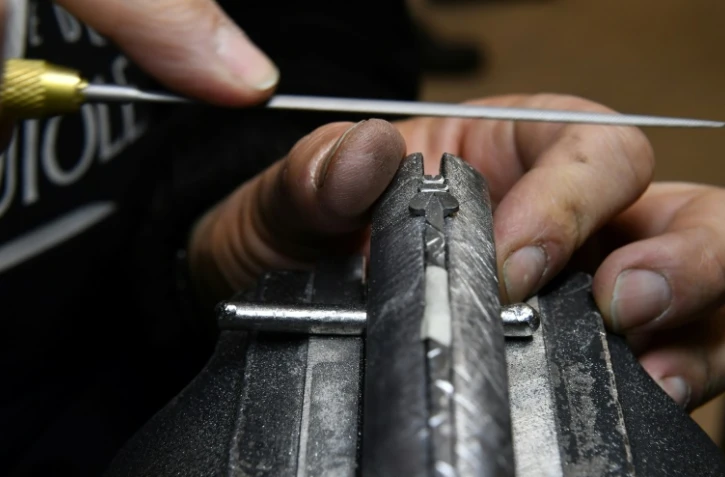 Un coutelier finalise l'abeille du ressort d'un Laguiole dans les ateliers de la Forge de Laguiole à Laguiole, dans l'Aveyron le 2 mars 2021