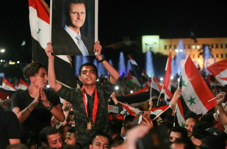 Des Syriens brandissent des drapeaux nationaux et le portrait de Bachar al-Assad le 27 mai 2021 à Damas, au lendemain de l'élection présidentielle pour laquelle il est donné vainqueur