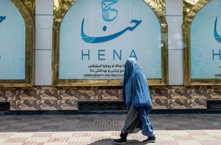 Une Afghane passe devant un salon de beauté à Kabul, le 25 juillet 2023