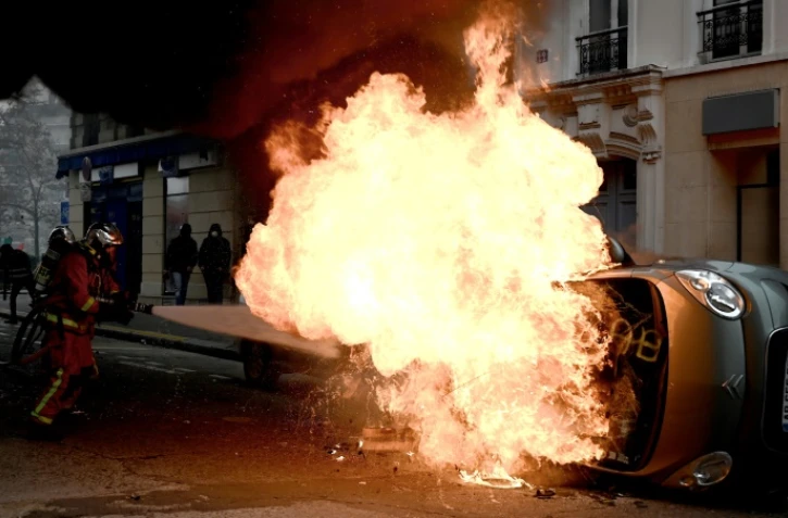 Un pompier tente d'éteindre le feu qui détruit une voiture place d'Italie à Paris, le 16 novembre 2019, en marge d'une manifestation des "gilets jaunes"