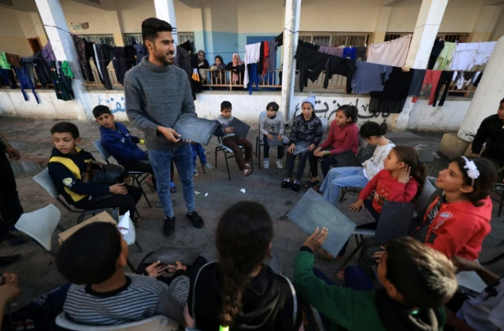 Tareq al-Ennabi, un Palestinien de 25 ans, donne un cours d'anglais à des enfants déplacés dans une école devenue camp de déplacés à Rafah, dans le sud de la bande de Gaza, le 29 novembre 2023