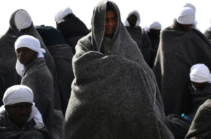 De smigrants se protègent du froid sous des couvertures à bord du navire de sauvetage "Aquarius" avant leur arrivée au port de Cagliari en Sardaigne le 26 mai 2016