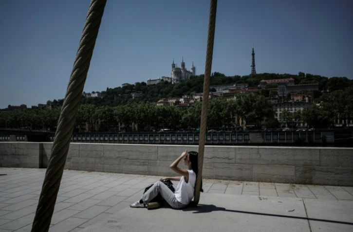Une personne est assise sur les quais de la Saône, à Lyon, le 26 mai 2026, alors qu'une vague de chaleur frappe la France