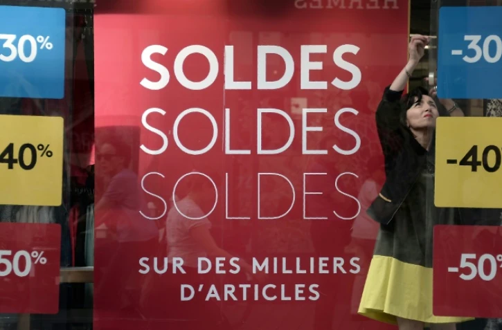 Une vendeuse s'occupe de la vitrine d'un magasin au lancement de la saison des soldes d'été le 22 juin 2016 à Strasbourg. Les pancartes affichent des réductions de 30, 40 et 50%