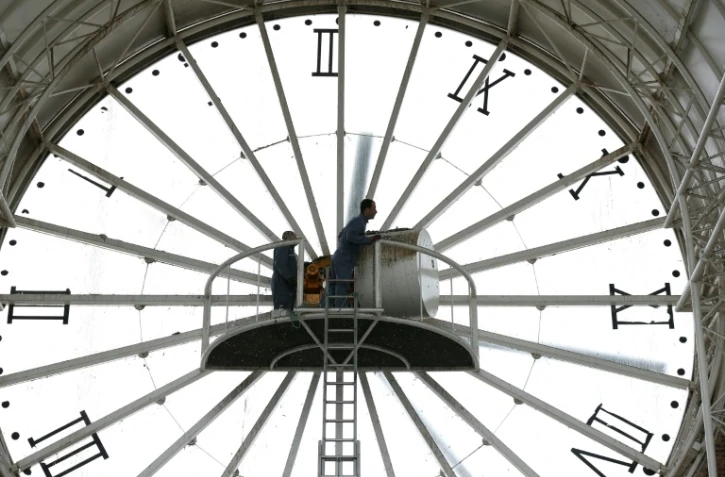 Un employé change l'heure d'une horloge géante à Cergy en prévision du passage à l'heure d'été le 26 mars 2015