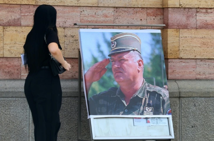 Une femme regarde un portrait de l'ancien chef militaire des Serbes de Bosnie, Ratko Mladić, devant la cathédrale orthodoxe de Banja Luka, en Bosnie, le 28 août 2026, au lendemain de sa mort à l'âge de 84 ans dans un hôpital pénitentiaire de La Haye