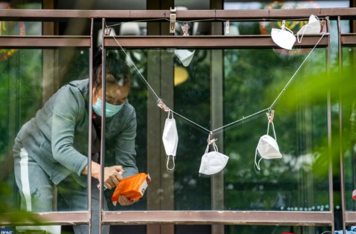 Un résident confiné désinfecte un sac de courses dans le district de Pudong à Shanghai le 1er mai 2022