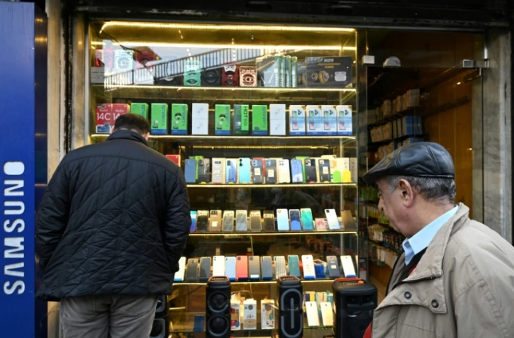 Un homme regarde la vitrine d'un magasin de téléphones à Damas, le 12 janvier 2025 en Syrie