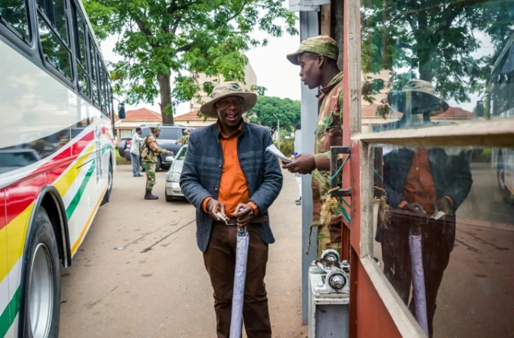 Un soldat contrôle des délégués à leur arrivée à une réunion cruciale du parti au pouvoir dimanche à Harare alors que le président Mugabe est lâché par ses principaux soutiens