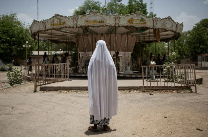 Une enfant regarde un manège d'un vieux parc d'attractions à l'abandon, le 27 avril 2017 à Maiduguri, au Nigeria