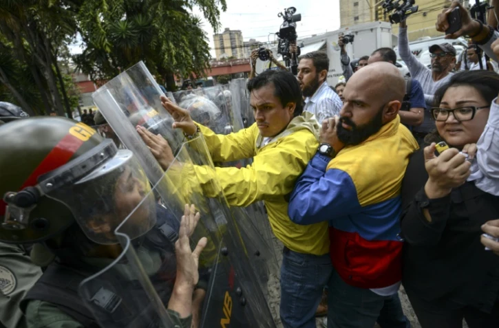 Carlos Paparoni (C) and Marco Bozo (D), députés d'opposition, face à la police, à Caracas, le 30 mars 