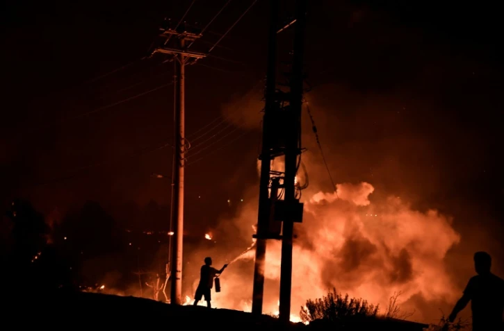 Un homme tente de lutter contre le feu avec un extincteur, le 3 août 2021 à Dekelia, au nord d'Athènes
