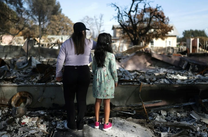 Deux soeurs regardent les restes de leur maison à Altadena, qui a brûlé dans les incendies de Los Angeles, le 2 février 2025 en Californie