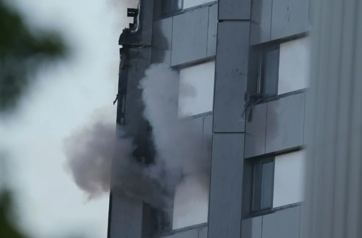 Une main tenant un tissu apparaît à la fenêtre d'un appartement d'une tour d'habitation ravagée par un incendie, le 14 juin 2017 à Londres