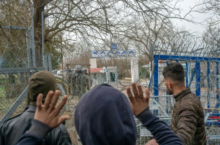 Des migrants s'adressent à la police grecque près du passage de la frontière entre la Turquie et la Grèce dans la région de Edirne, le 4 mars 2020