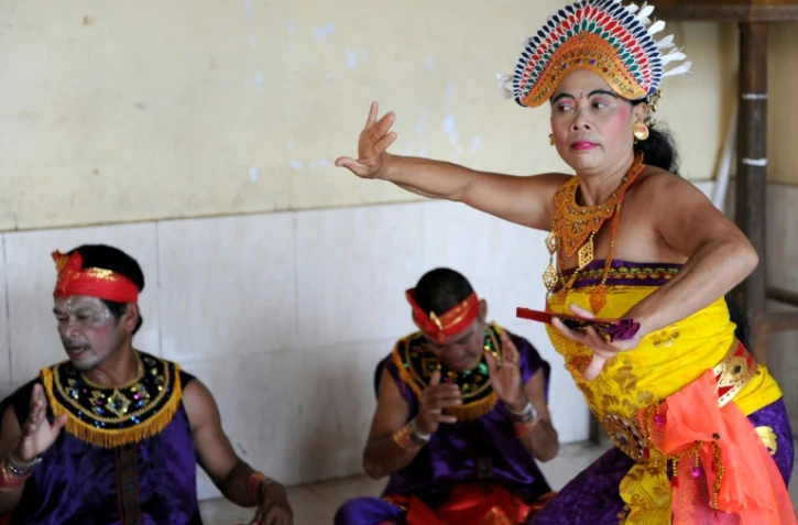 Des Balinaises en corsage doré dansent sur une musique traditionnelle devant des hommes assis par terre jambes croisées autour d'elles en remuant leurs mains. Un show dont tous les acteurs sont sourds