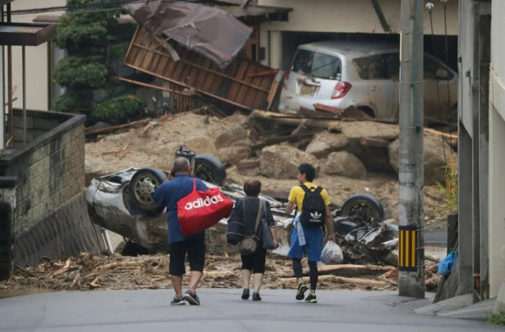 Des habitants traversent leur quartier dévasté à Hiroshima après des pluies meurtrières au Japon, le 8 juillet 2018