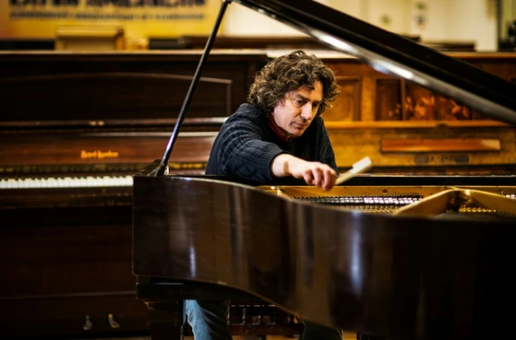 Le musicien Tim Vincent-Smith, co-directeur de "Pianodrome", accorde un piano qui a été restauré, le 9 février 2023 à Edimbourg, en Ecosse