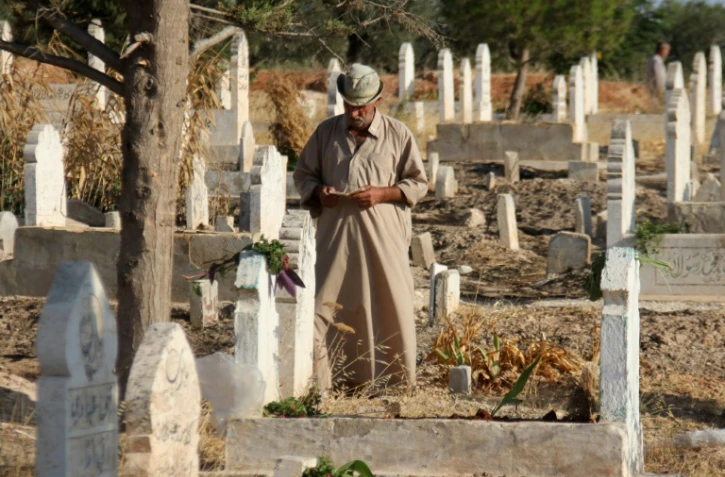 Un Syrien lit le coran sur les tombes de proches et de membres de sa famille au premier jour de l'Aïd al-Adha, la grande fête musulmane du sacrifice, le 1er septembre 2017 à Binnish (Syrie)

