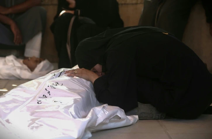 Des Palestiniens veillent un proche tué par une frappe israélienne, à Khan Younès, dans le sud de la bande de Gaza, le 22 juillet 2025